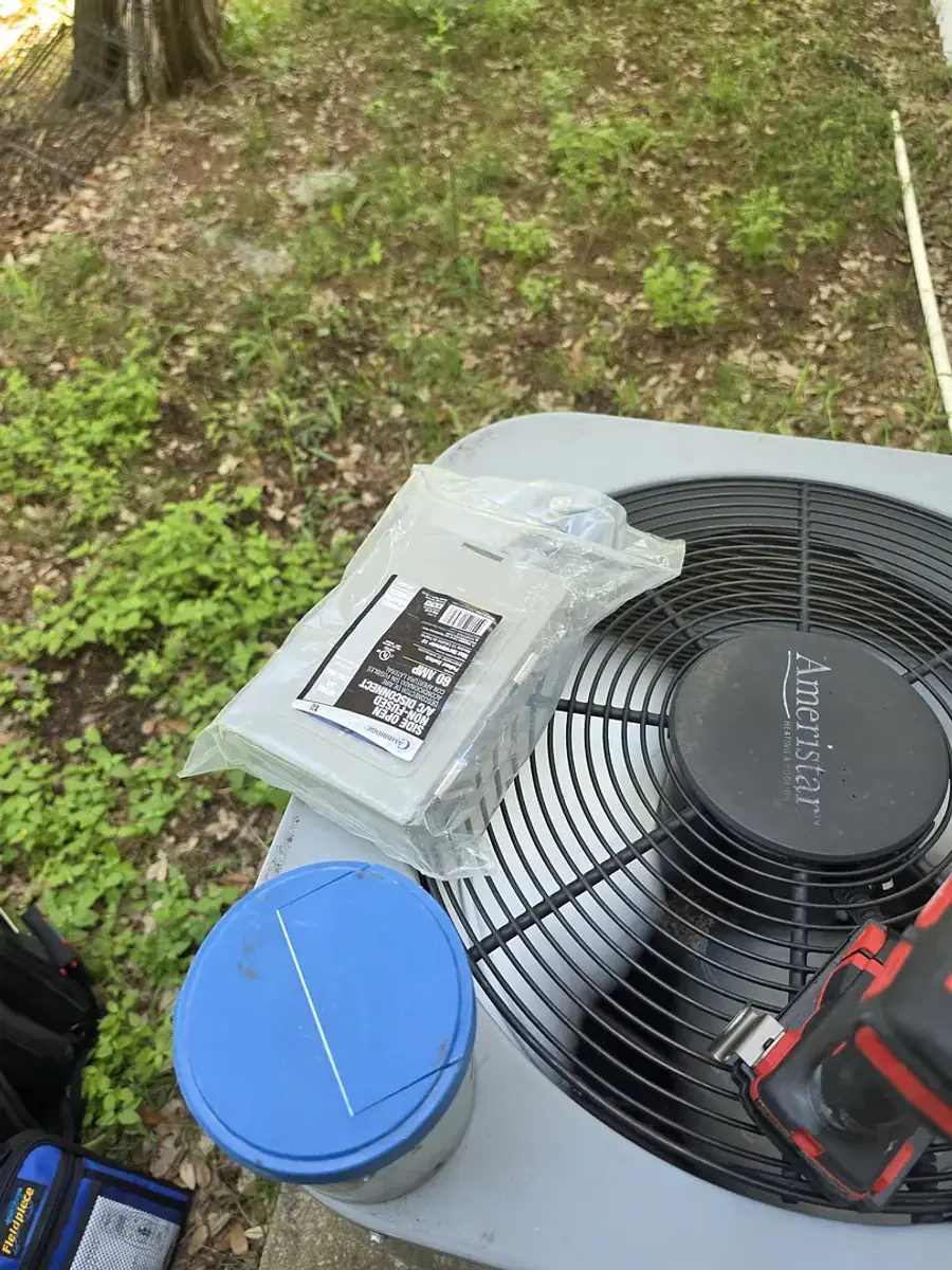 New sealed parts and hand tools laid out across the top grille of an Ameristar condenser.